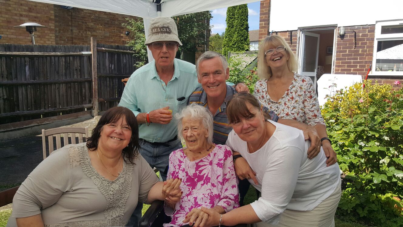 A family of six gathered in the garden — three generations together on a summer afternoon
